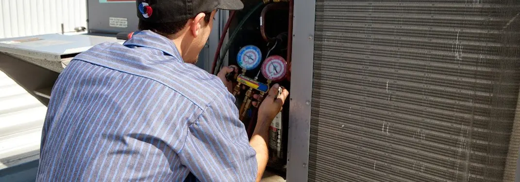 HVAC technician servicing a condenser unit in Coronado